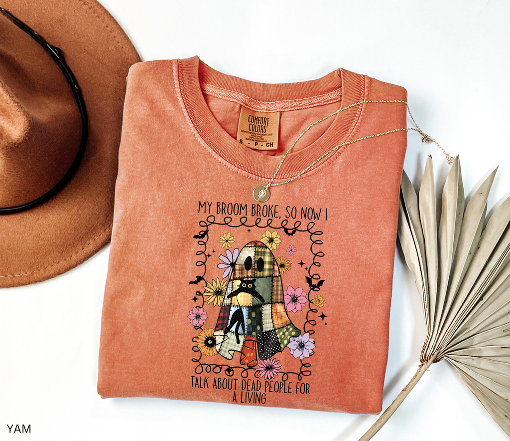 Halloween shirt with a patchwork quilt ghost holding a black cat, surrounded by colorful flowers. Cute cozy spooky season tee.