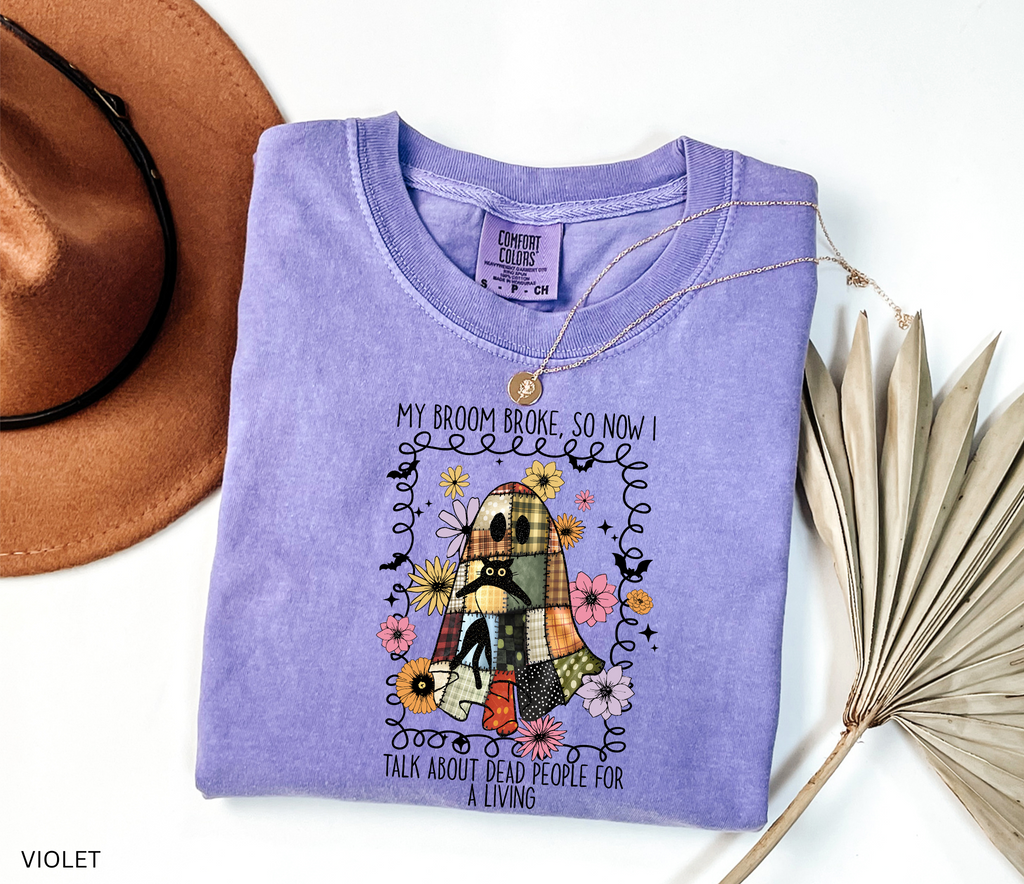 Halloween shirt with a patchwork quilt ghost holding a black cat, surrounded by colorful flowers. Cute cozy spooky season tee.