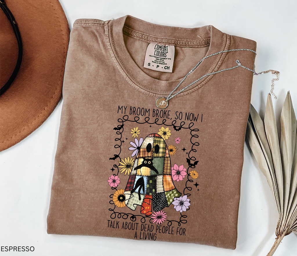 Halloween shirt with a patchwork quilt ghost holding a black cat, surrounded by colorful flowers. Cute cozy spooky season tee.