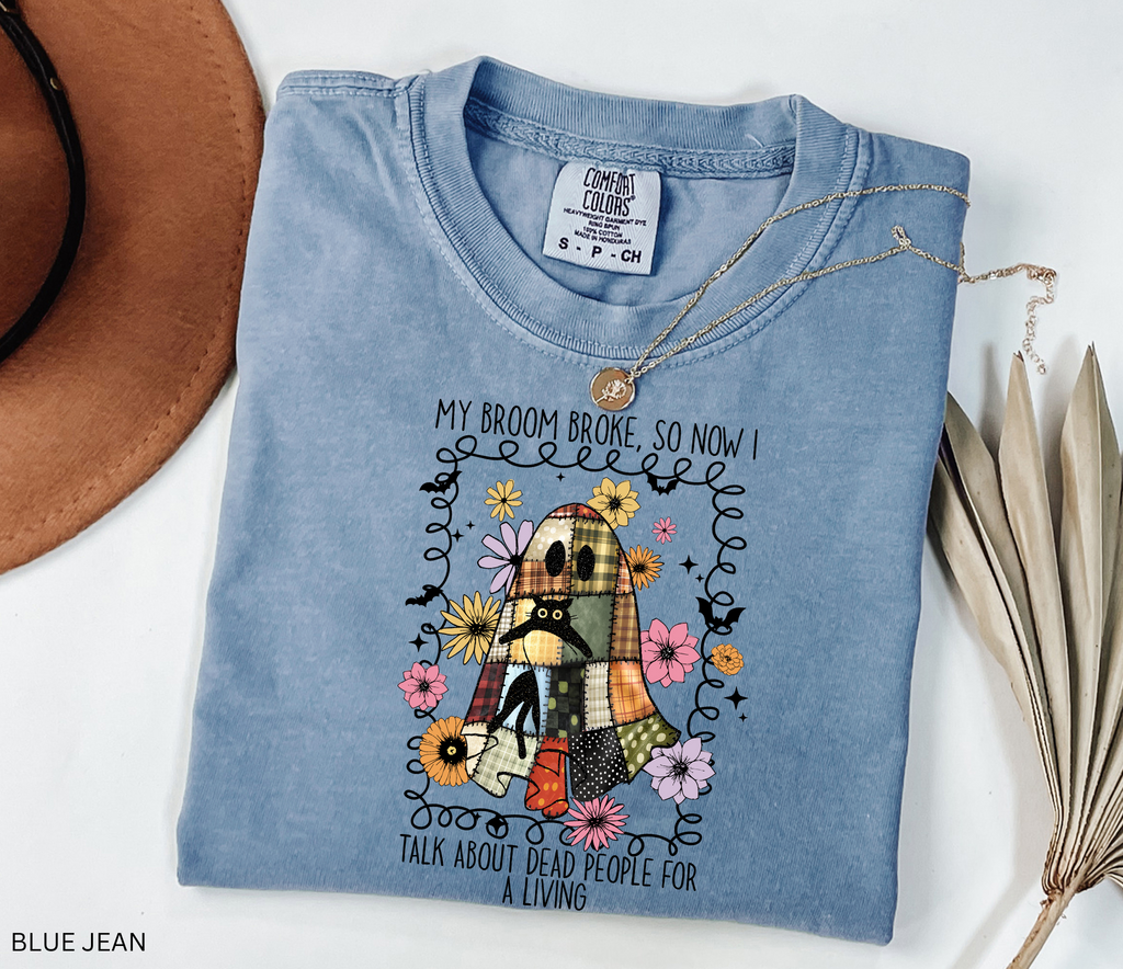 Halloween shirt with a patchwork quilt ghost holding a black cat, surrounded by colorful flowers. Cute cozy spooky season tee.