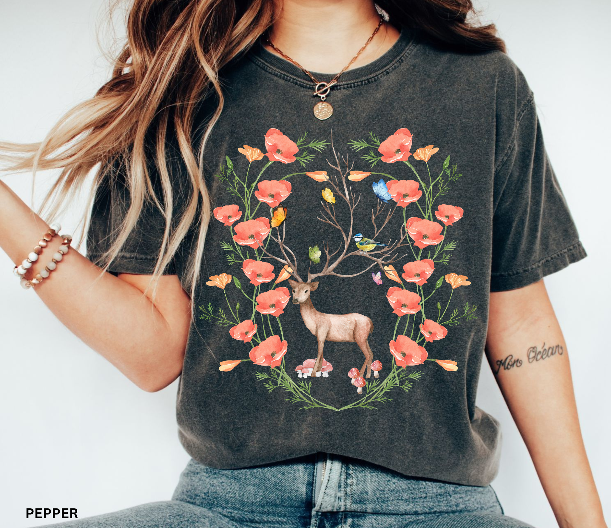 Watercolor woodland deer surrounded by flowers, mushrooms, butterflies, and birds printed on a vintage-style Comfort Colors cottagecore shirt