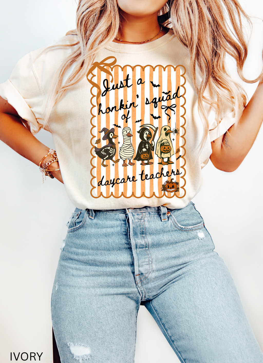 Halloween daycare teacher shirt featuring four geese dressed in spooky costumes (witch, mummy, reaper, ghost) with pumpkins, bats, and candy on orange striped background. Perfect group Halloween tee for daycare teachers.