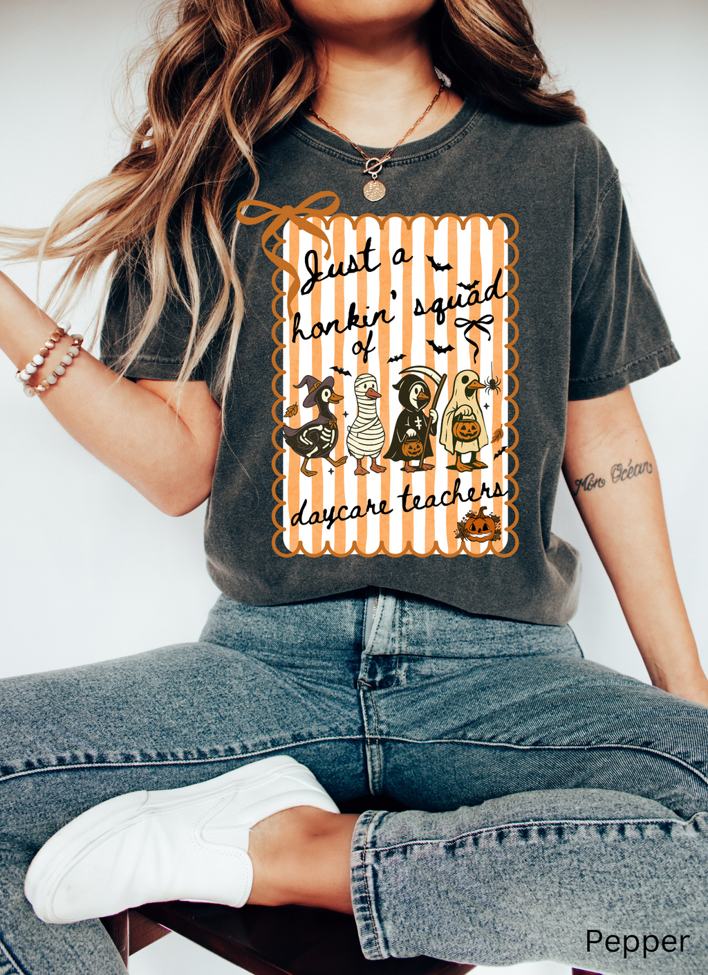 Halloween daycare teacher shirt featuring four geese dressed in spooky costumes (witch, mummy, reaper, ghost) with pumpkins, bats, and candy on orange striped background. Perfect group Halloween tee for daycare teachers.