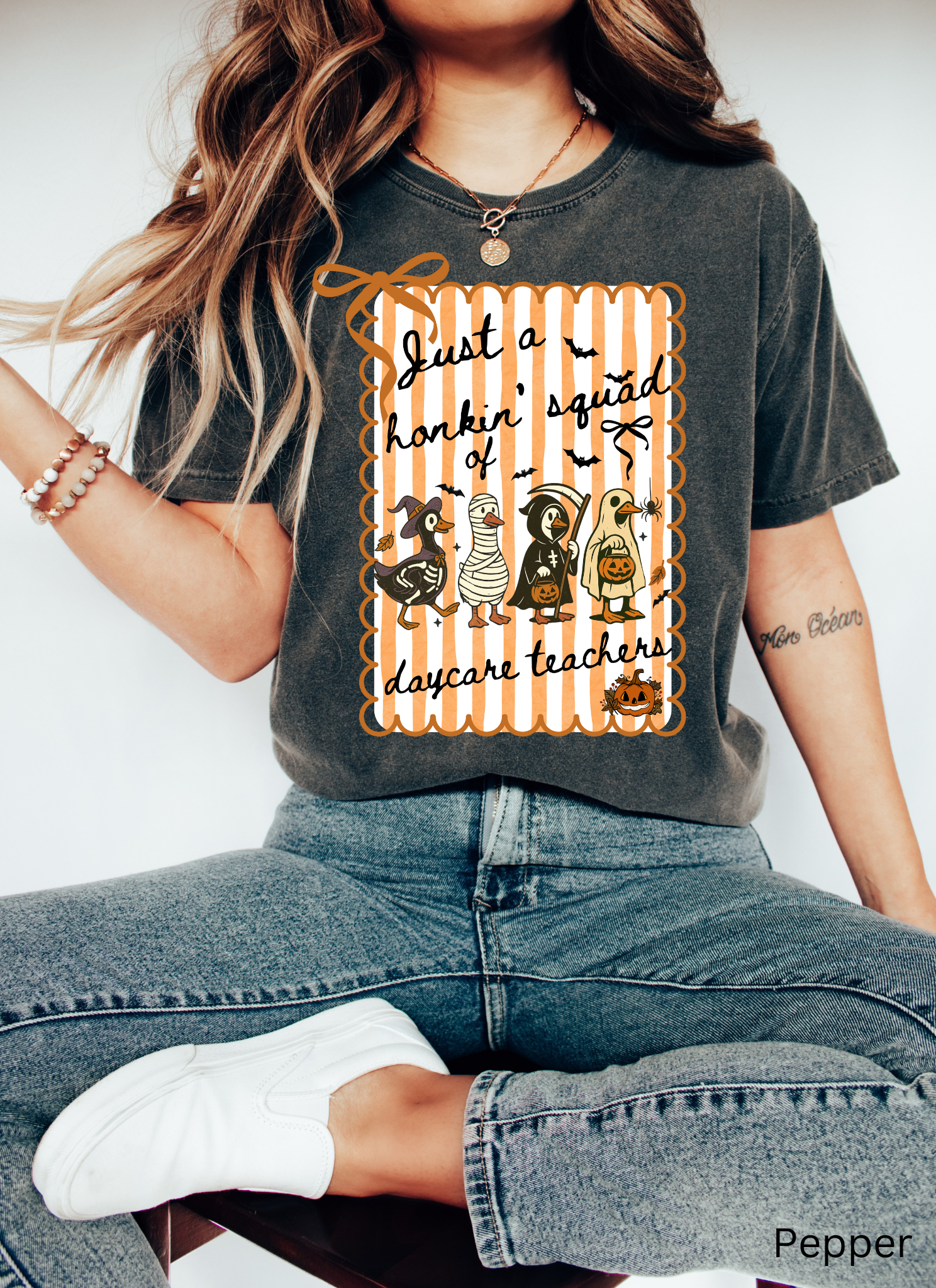Halloween daycare teacher shirt featuring four geese dressed in spooky costumes (witch, mummy, reaper, ghost) with pumpkins, bats, and candy on orange striped background. Perfect group Halloween tee for daycare teachers.
