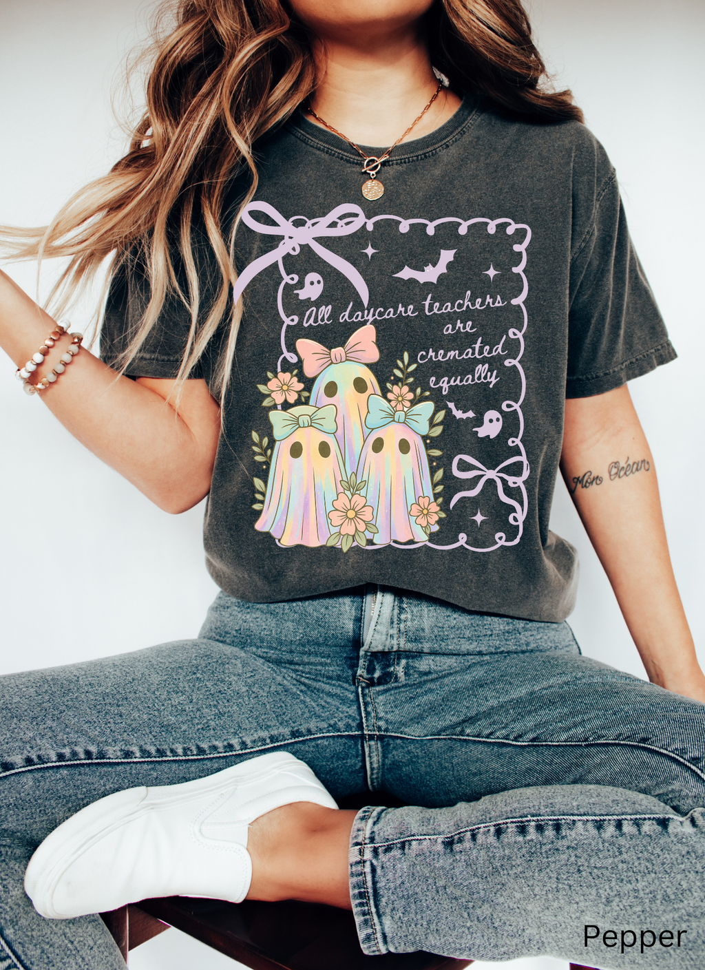 Halloween daycare teacher shirt with three pastel rainbow ghosts wearing bows, surrounded by flowers. Cute and spooky teacher tee for childcare staff.