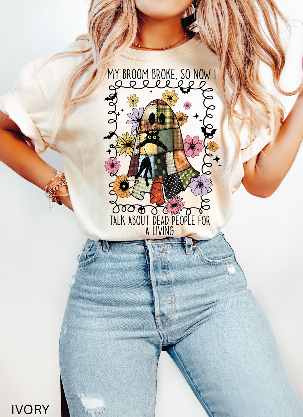 Halloween shirt with a patchwork quilt ghost holding a black cat, surrounded by colorful flowers. Cute cozy spooky season tee.