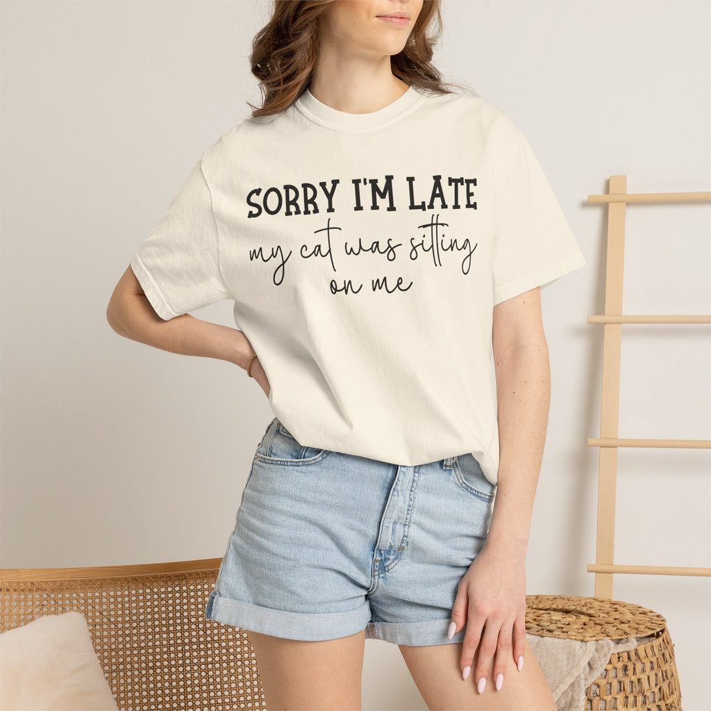 Funny cat lover graphic t-shirt featuring the quote "Sorry I'm Late My Cat Was Sitting on Me." A humorous gift for cat moms, cat dads, and anyone owned by a sleepy cat.