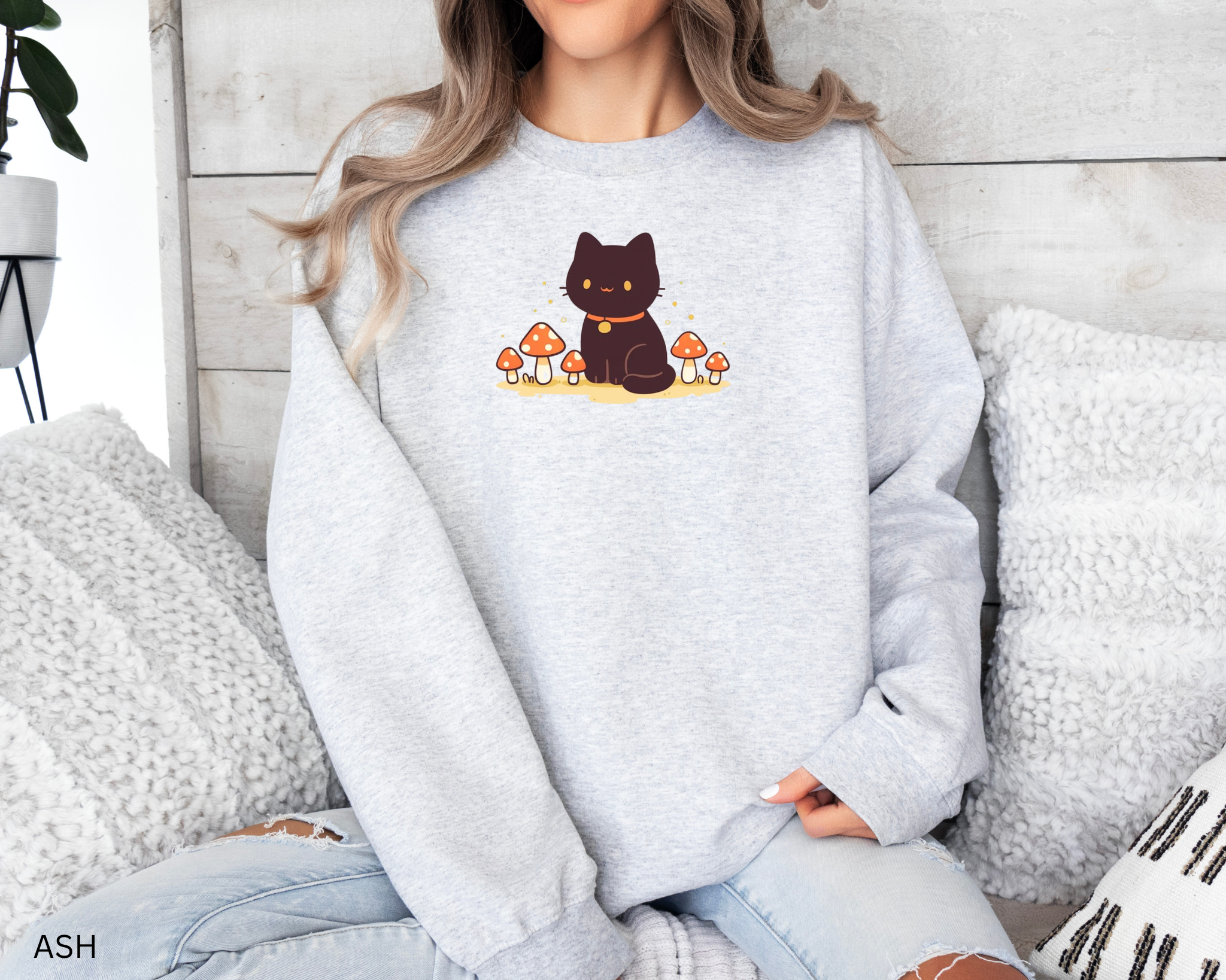 A cozy Comfort Colors sweatshirt featuring a cute black cat sitting among red mushrooms, perfect for cottagecore and witchy aesthetic lovers.