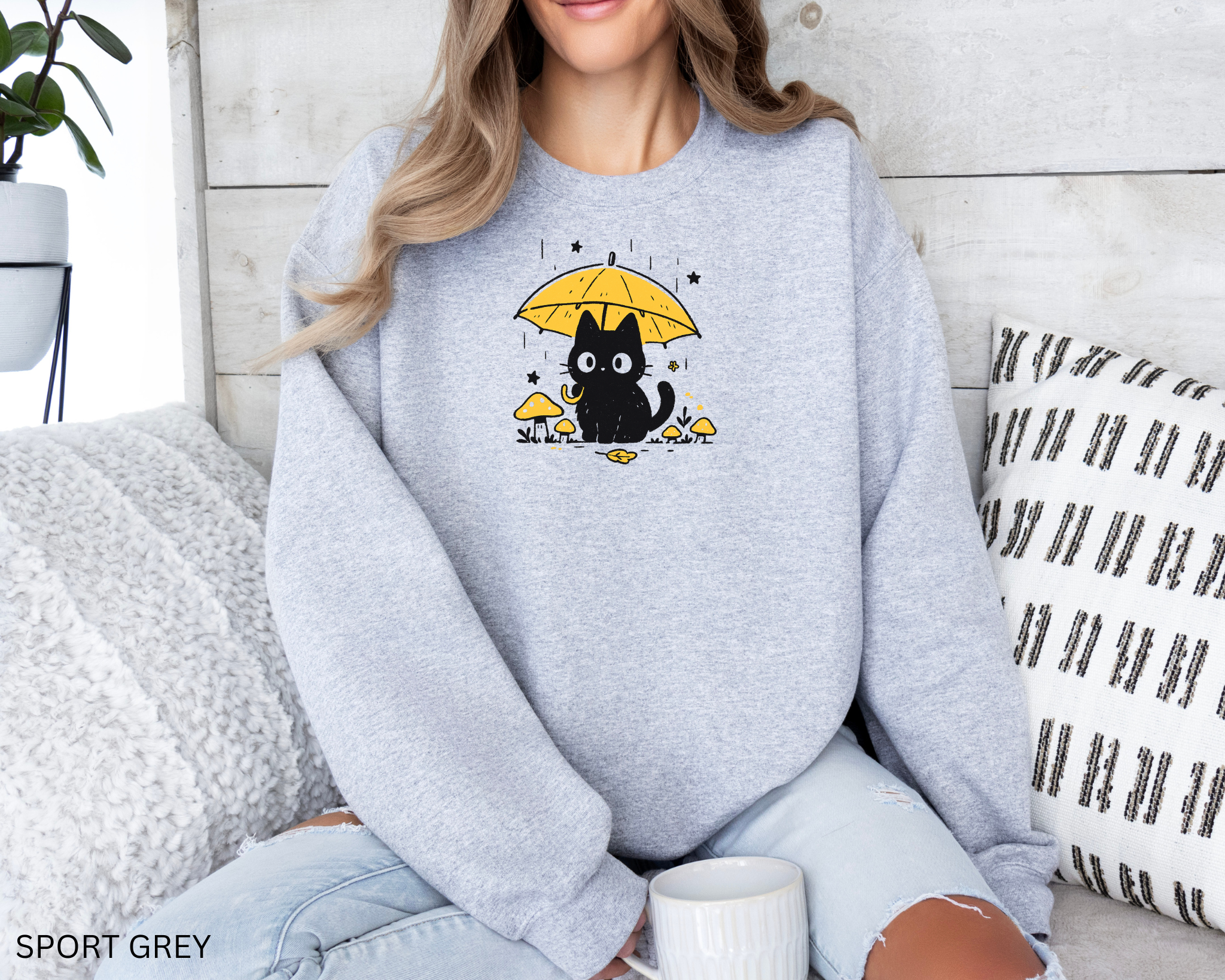 Black cat sitting under a yellow umbrella with mushrooms and stars, printed on a cozy grey sweatshirt
